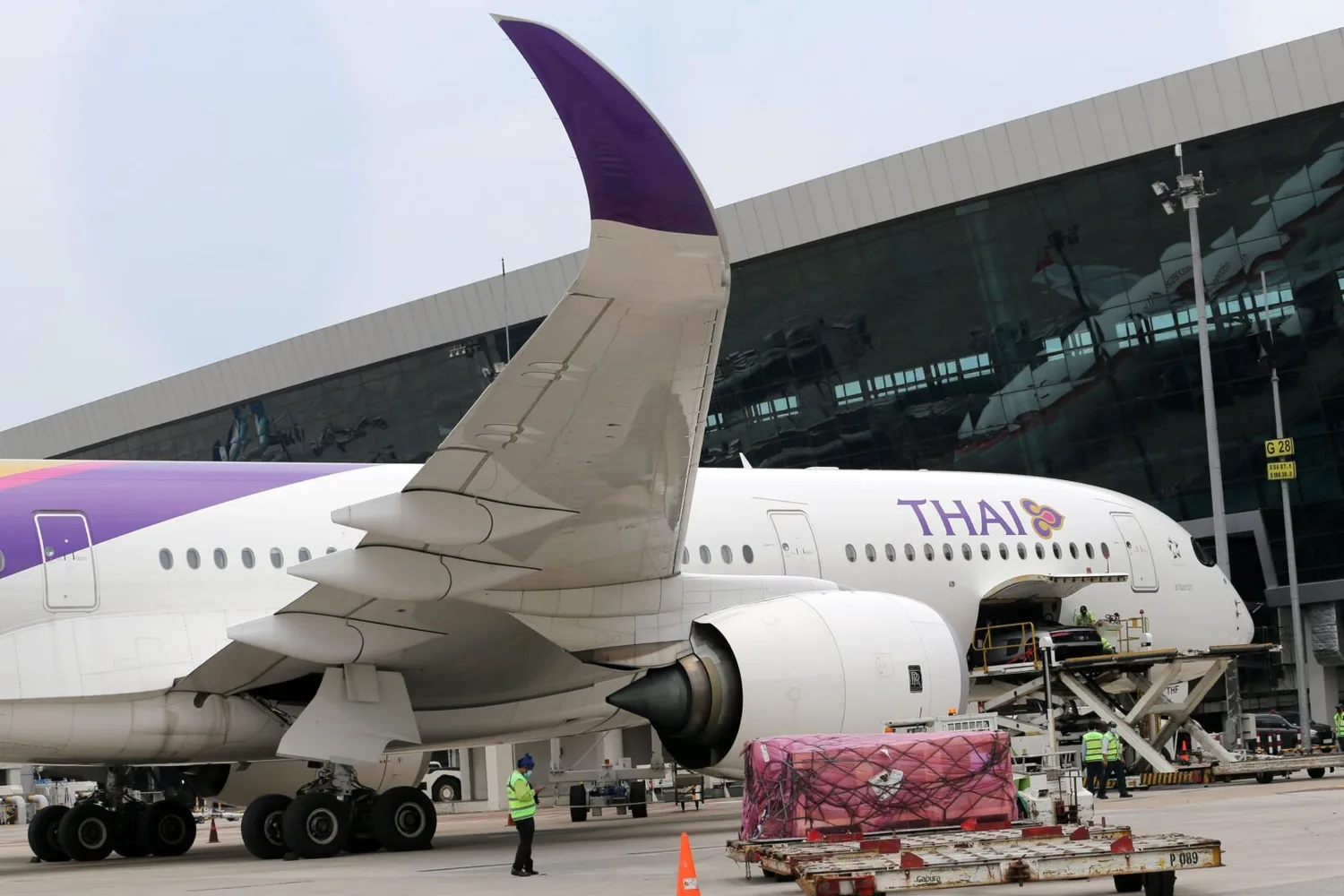 Thai Airways Passagierflugzeug am Gate mit geöffnetem Frachtraum, Bodenpersonal und Gepäckverladung sichtbar