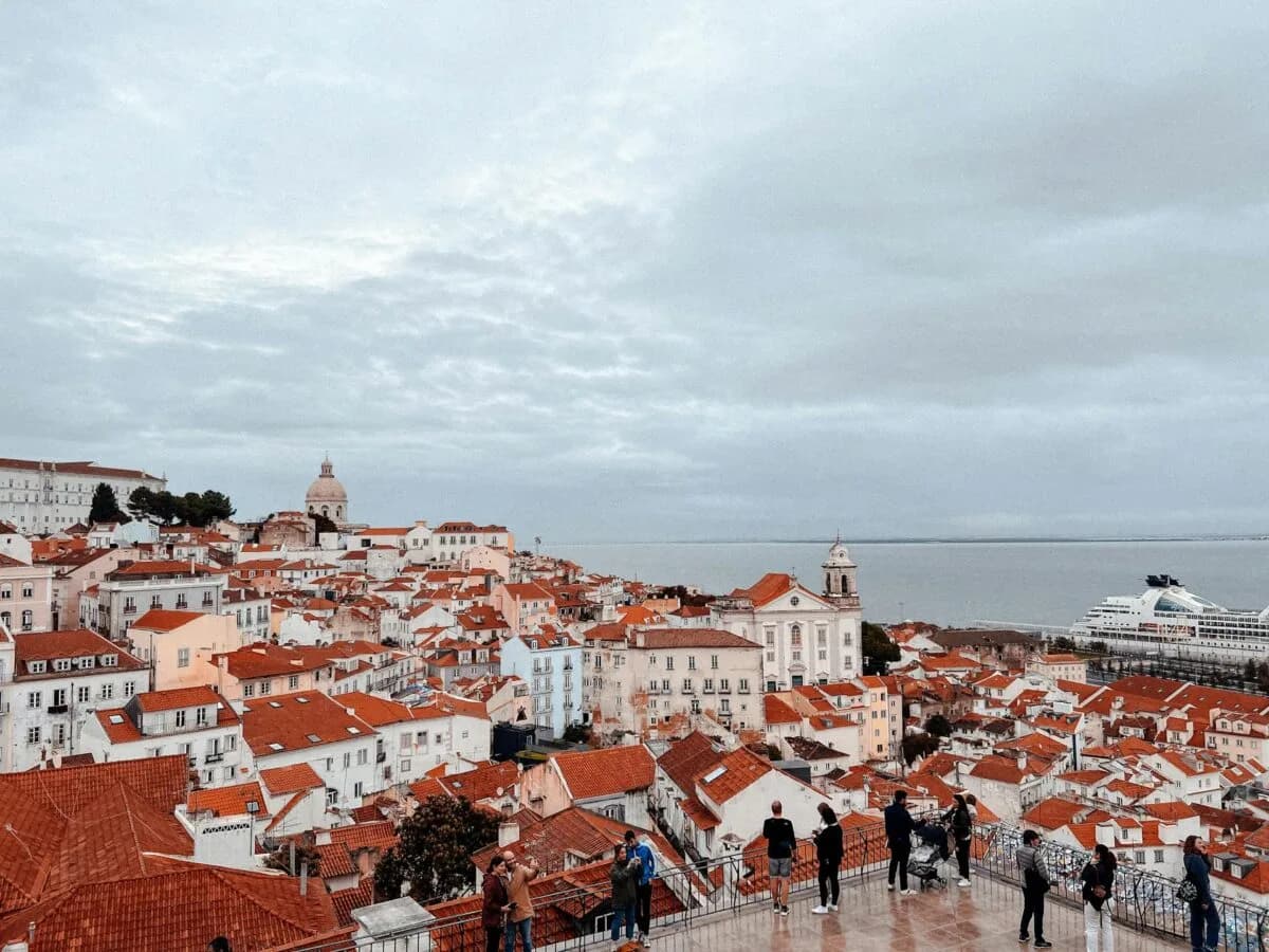 Panoramablick auf Lissabon mit roten Dächern, historischen Gebäuden, Kirchenkuppel und Tejo-Fluss im Hintergrund