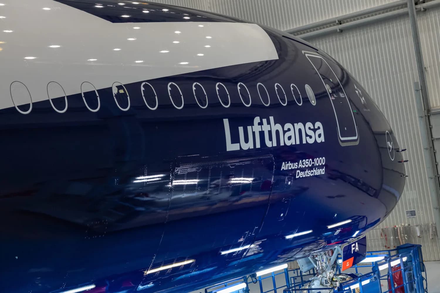 Lufthansa Airbus A350-1000 Rumpfdetail mit Fensterreihe und geöffneter Wartungstür in Hangar, dunkelblaue Lackierung und Lufthansa-Logo