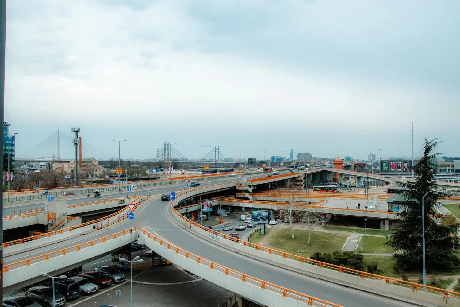Vielspuriger Autobahnkreuz mit Auffahrten und Brücken in Belgrad, Serbien, Blick auf Verkehr, Parkplätze und moderne Stadtbrücke im Hintergrund