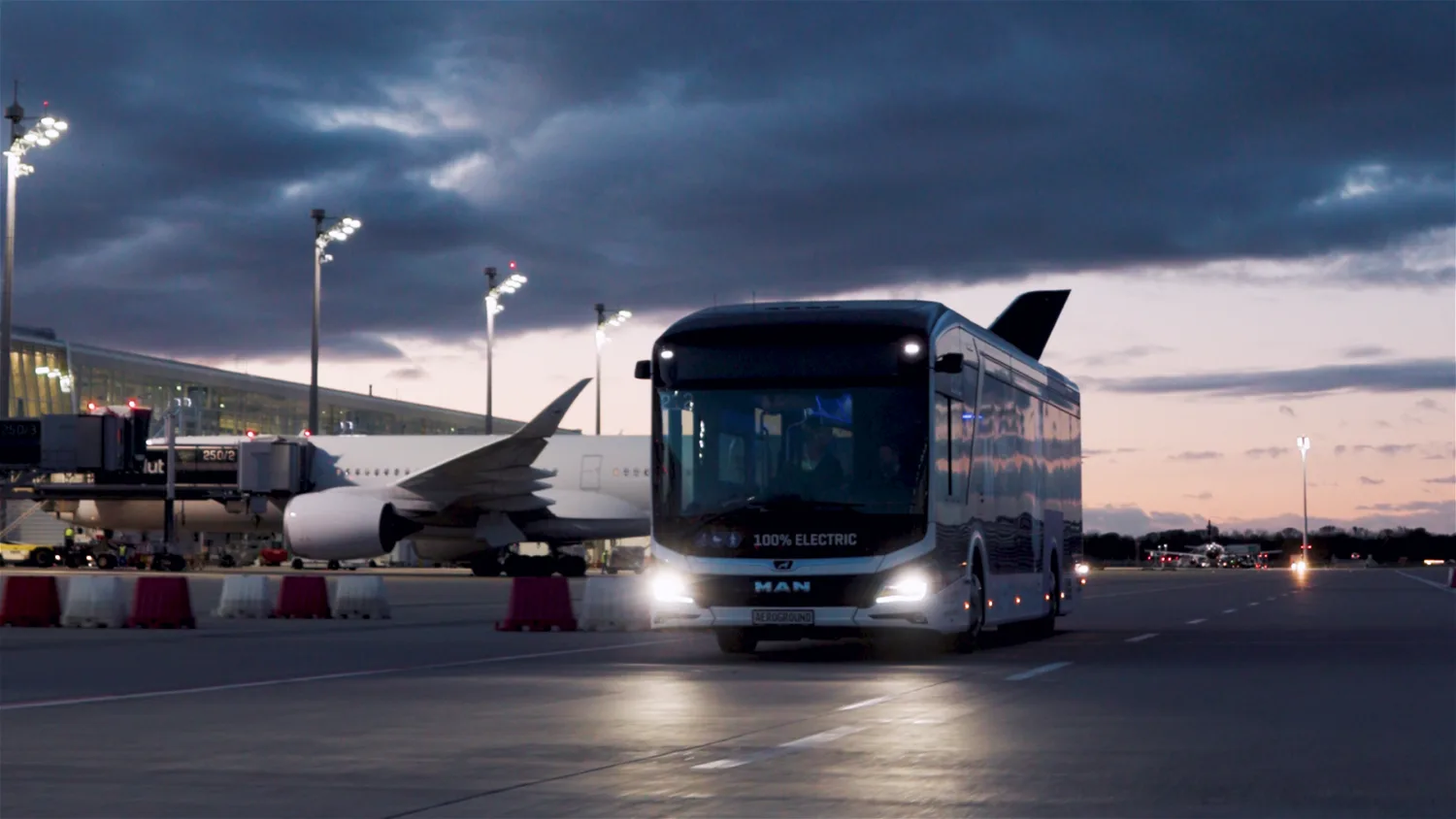 Elektro-Flughafenbus LionsCity E Aeroground vor passendem Passagierflugzeug am Abend auf dem Vorfeld