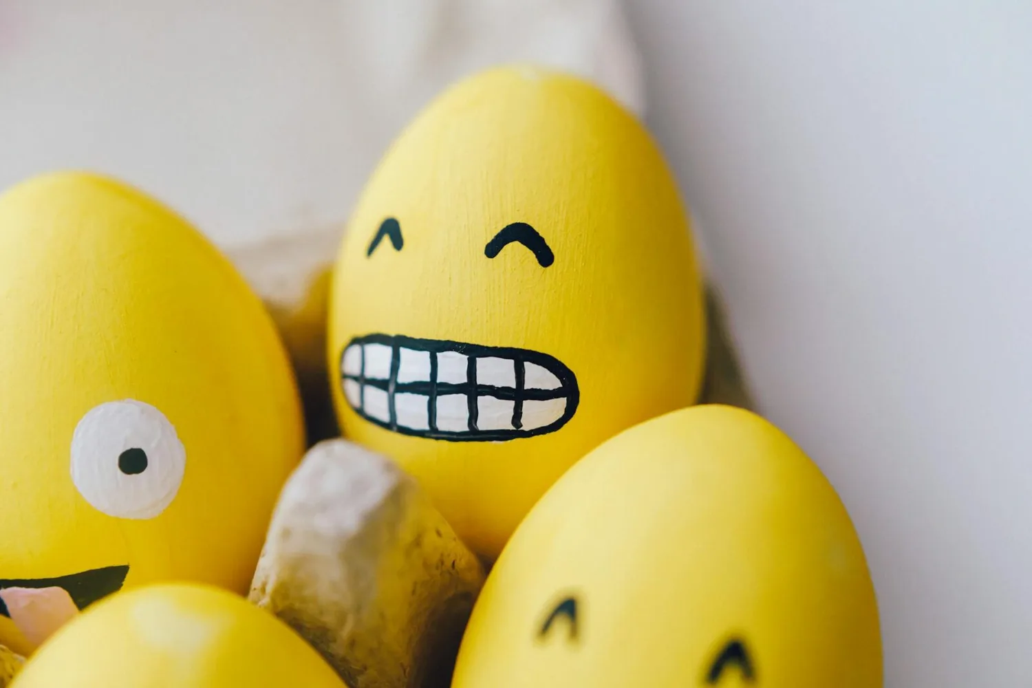 Gelb bemalte Oster-Eier mit lachenden Emoji-Gesichtern in Eierkarton, Osterferien Stimmung am Flughafen München