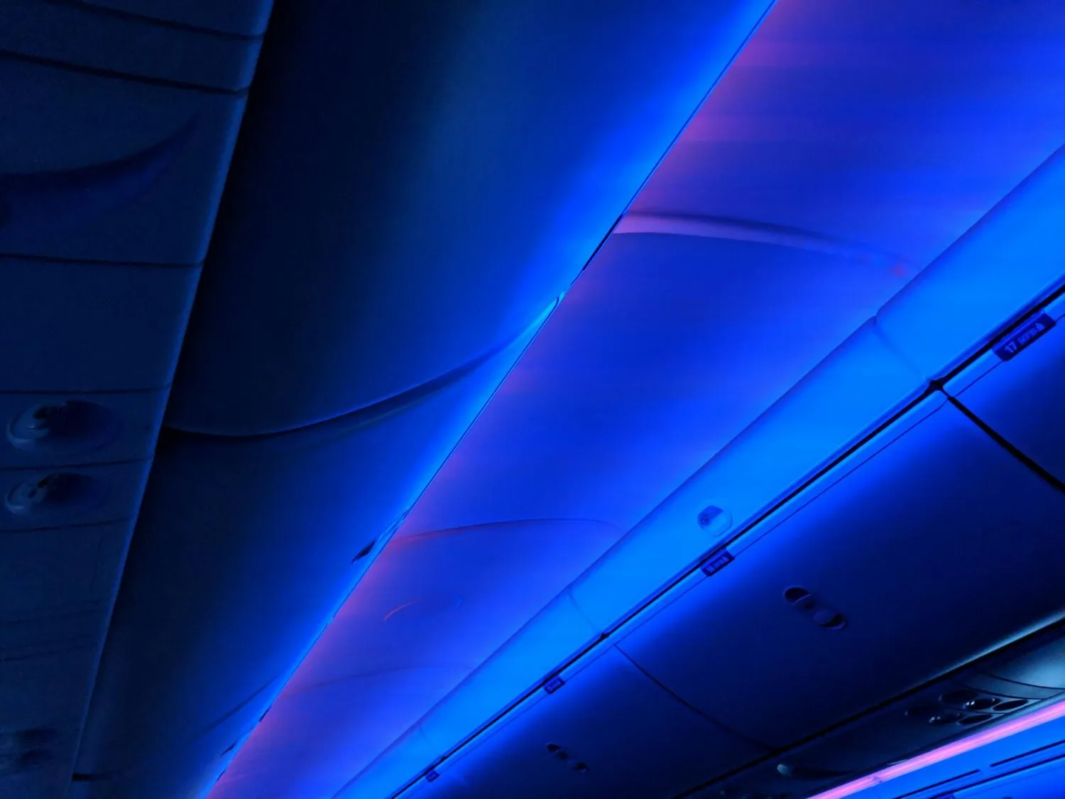 Innenraumdecke eines Flugzeugs mit blau-violetter Ambientebeleuchtung, Kabinenverstaukästen und Lüftungsdüsen, Atmosphäre bei Flughafen München Pressekonferenz zum Schneechaos