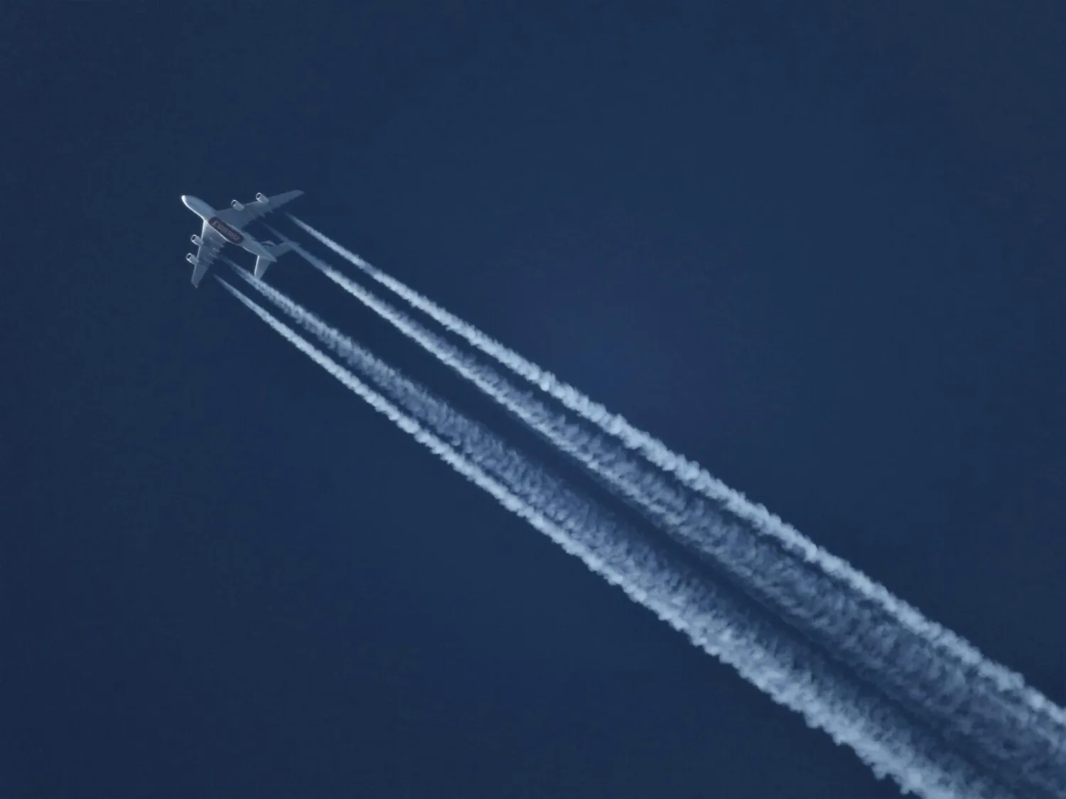 Passagierflugzeug mit Kondensstreifen am klaren Himmel, Symbol für Flugreisen und optimale Buchungszeiten ab Flughafen München