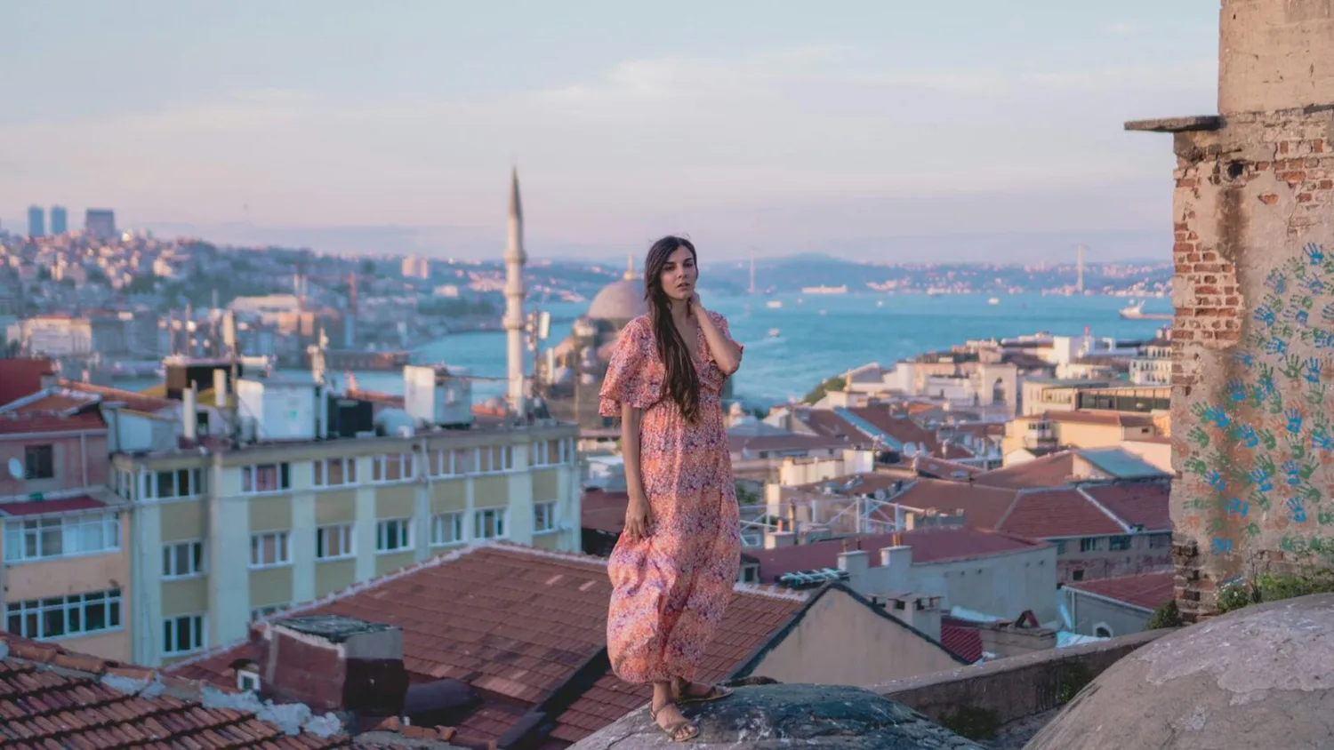 Frau im Sommerkleid auf Dach mit Blick über Istanbuls Skyline, Bosporus, Moschee und rote Ziegeldächer