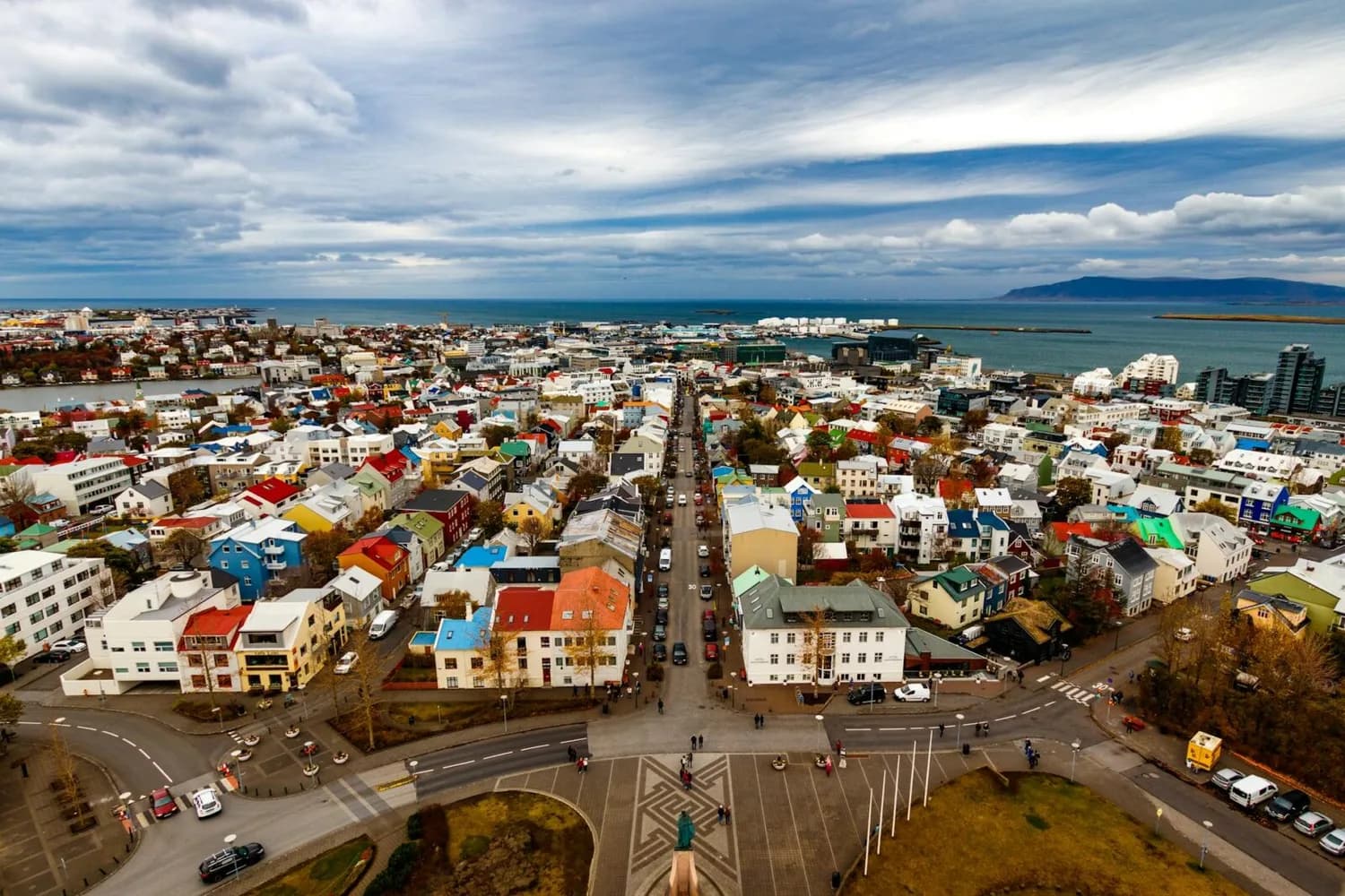Panoramablick auf Reykjavíks bunte Häuser, gerade Straße zum Hafen und Atlantik im Hintergrund, Stadtansicht für Kurztrip in Europa