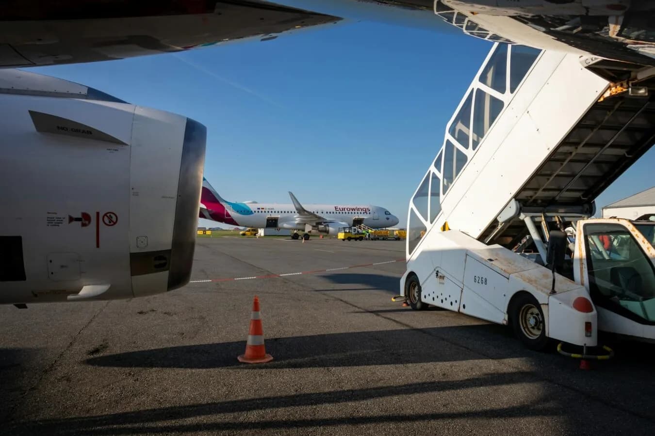 Eurowings Passagierflugzeug am Flughafen München mit mobiler Passagiertreppe und Bodenfahrzeugen auf dem Vorfeld bei klarem Himmel