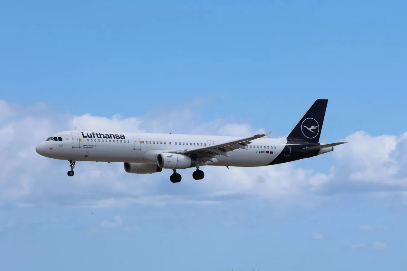 Lufthansa Passagierflugzeug im Landeanflug vor blauem Himmel, Lufthansa-Logo am Heck