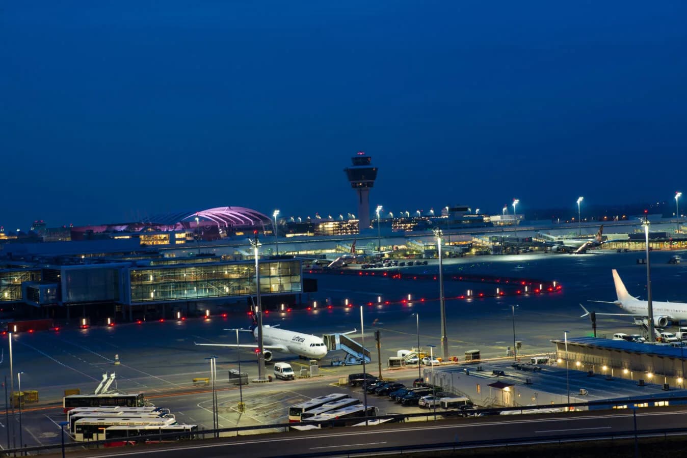Blick auf Jets, die auf dem Asphalt im Flughafen München vor einem Terminal geparkt sind