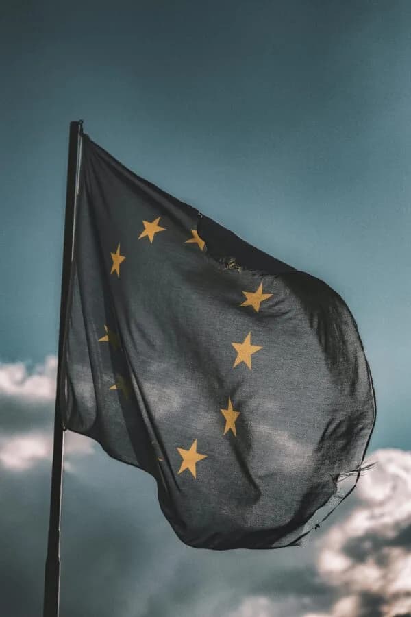 Europaflagge mit gelben Sternen im Wind vor bewölktem Himmel, Symbolbild zu Europa und Flugverspätungen