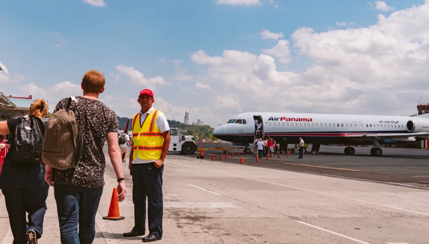 Passagiere steigen über das Vorfeld in ein Air Panama Flugzeug ein, Bodenpersonal mit Warnweste und Flughafenfahrzeug im Hintergrund, sonniger Tag