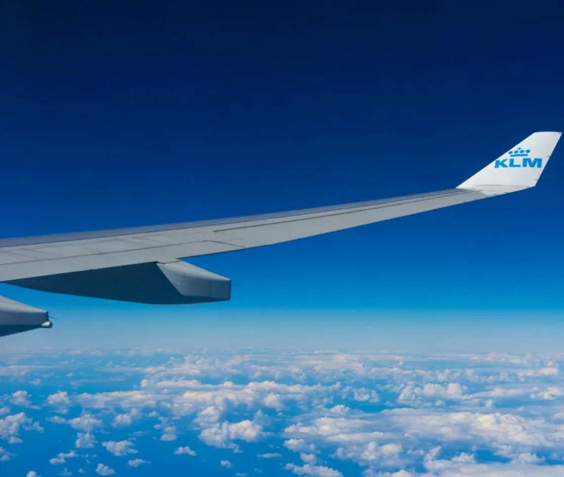 Flugzeugflügel mit KLM-Logo über Wolkenpanorama, Blick aus dem Passagierfenster während eines Fluges Richtung Bremen Amsterdam parksleepfly
