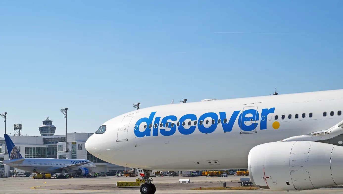 Discover Airlines Passagierflugzeug am Flughafen München mit Terminal und Tower im Hintergrund