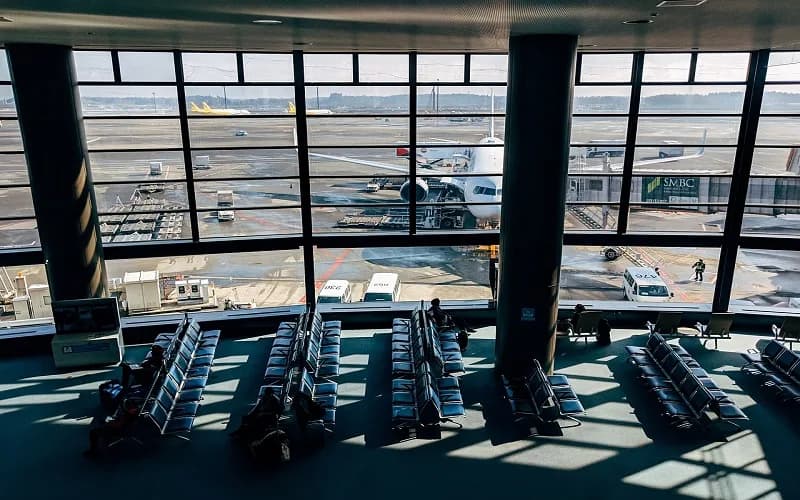 Wartehalle am Flughafen München mit leeren Sitzreihen, Blick auf Flugzeug am Gate und Bodenfahrzeuge während eines Streiks