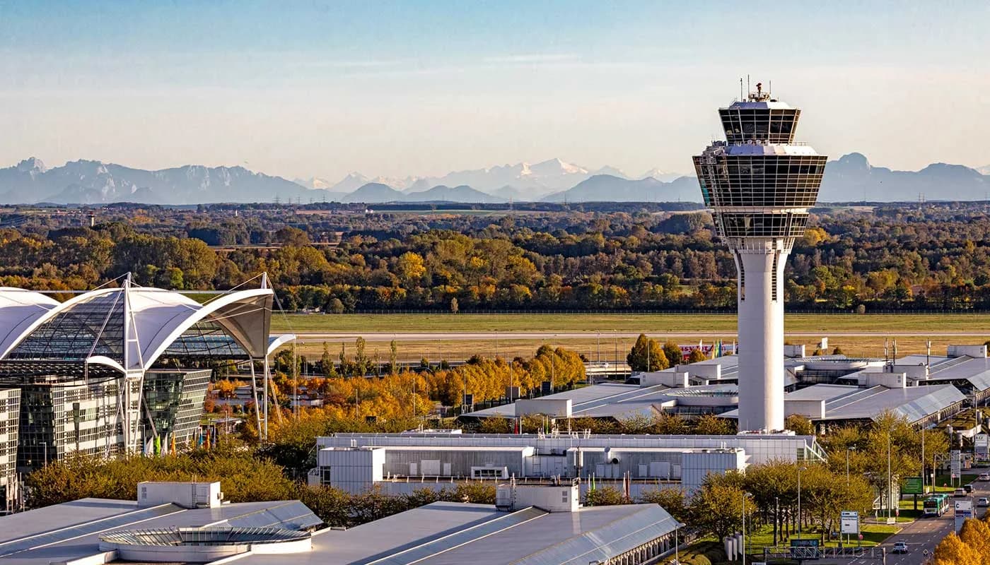 Flughafen München mit markantem Tower, Terminaldach und Alpenpanorama im Hintergrund