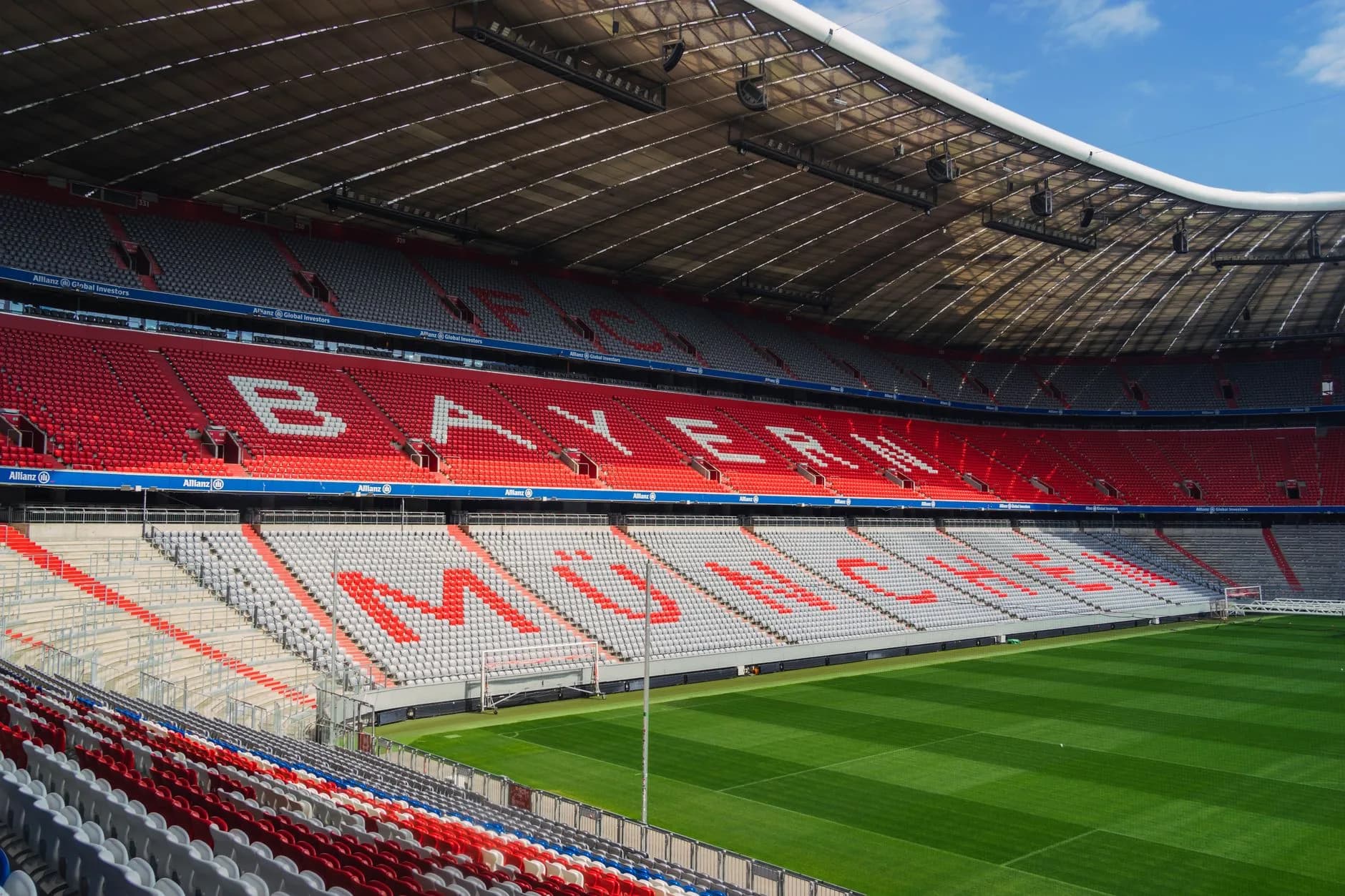 Leere Tribüne der Allianz Arena mit Schriftzug Bayern München in den Sitzreihen und Blick auf den Rasen