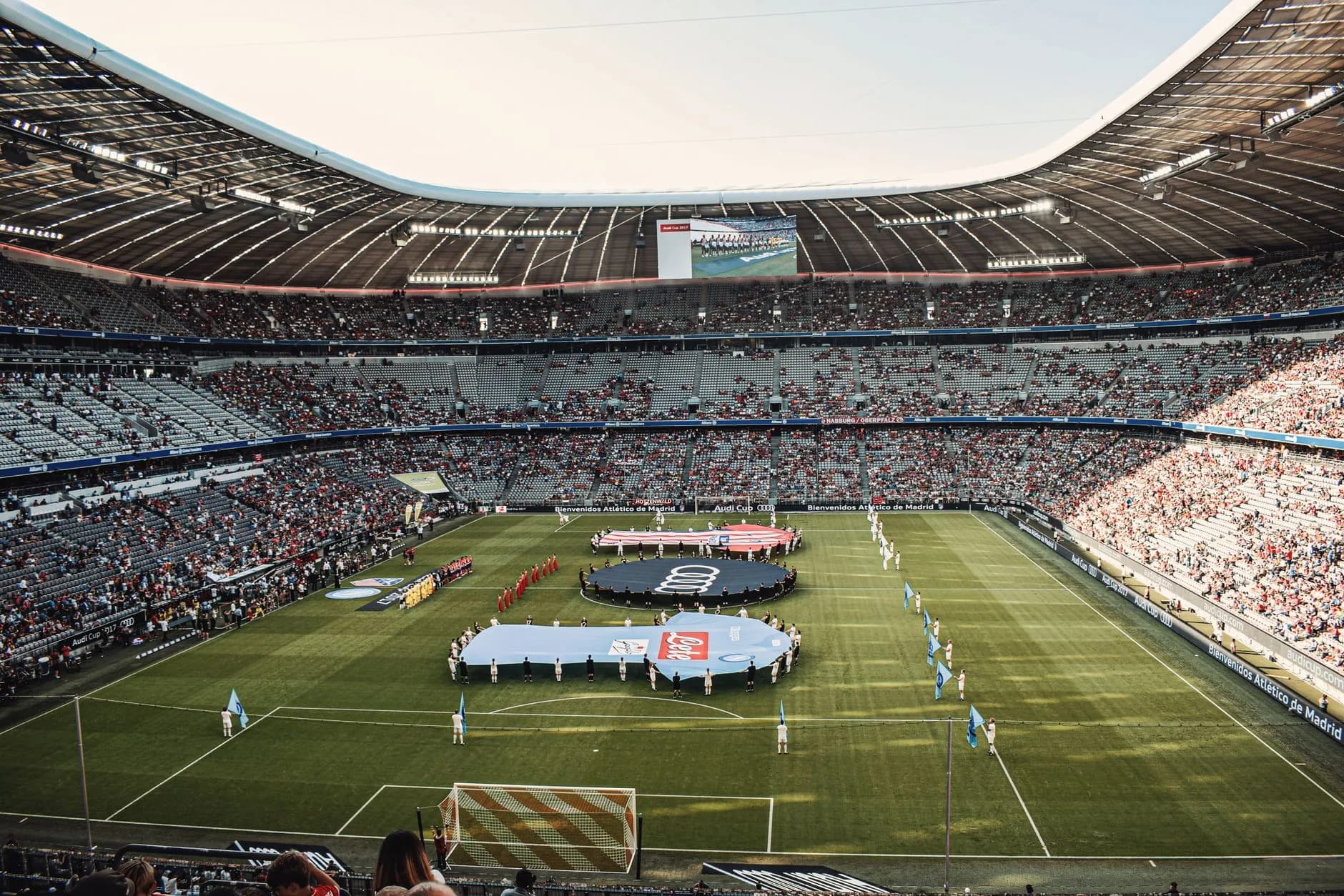 Blick über ein volles Fußballstadion mit Mannschaften und Bannern auf dem Rasen vor Spielbeginn