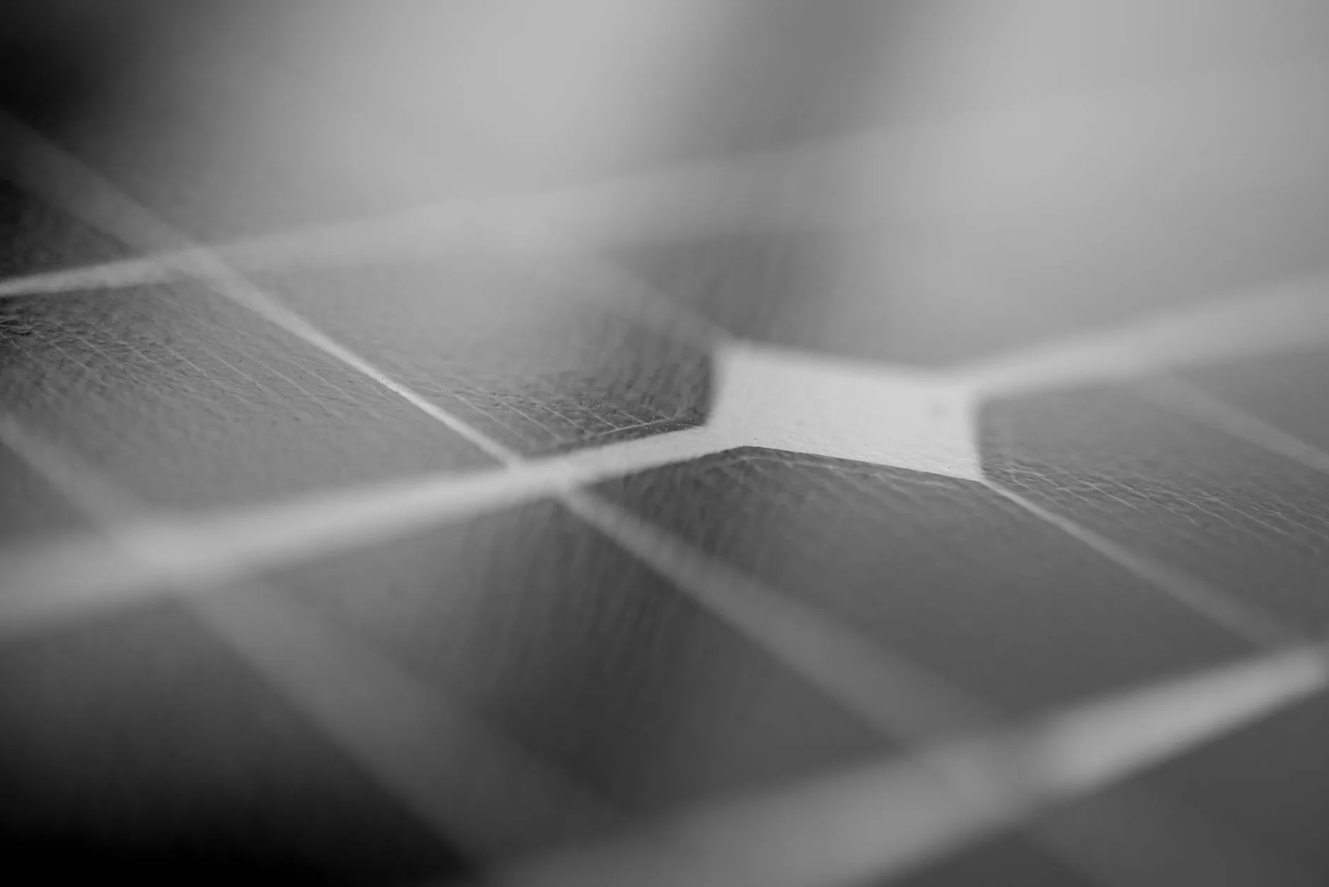 Nahaufnahme einer Solarzelle in Schwarz-Weiß mit sichtbaren Zellstrukturen und Verbindungslinien