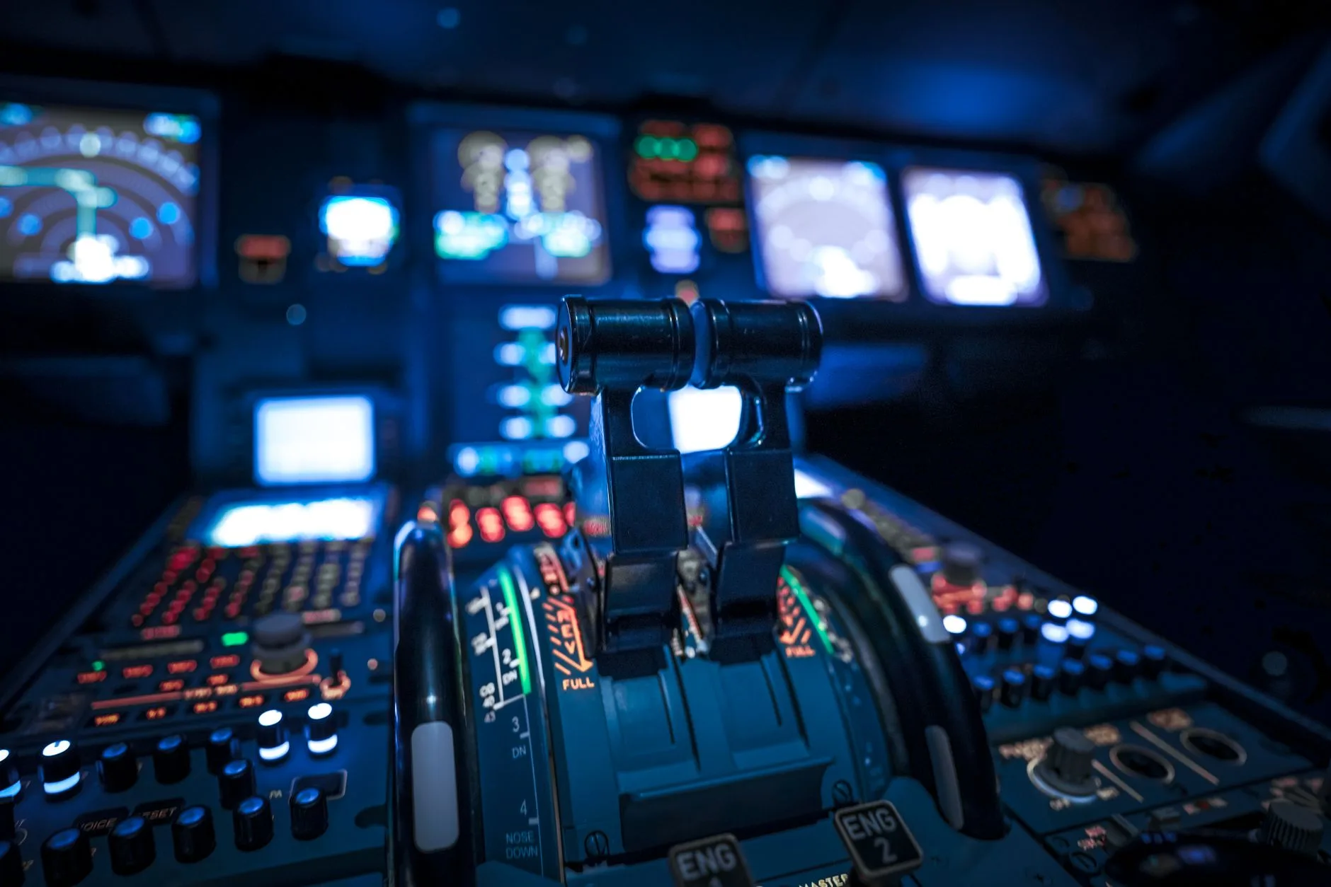 Cockpit eines Flugzeugs mit beleuchteten Schubhebeln und zahlreichen Anzeigen im Dämmerlicht