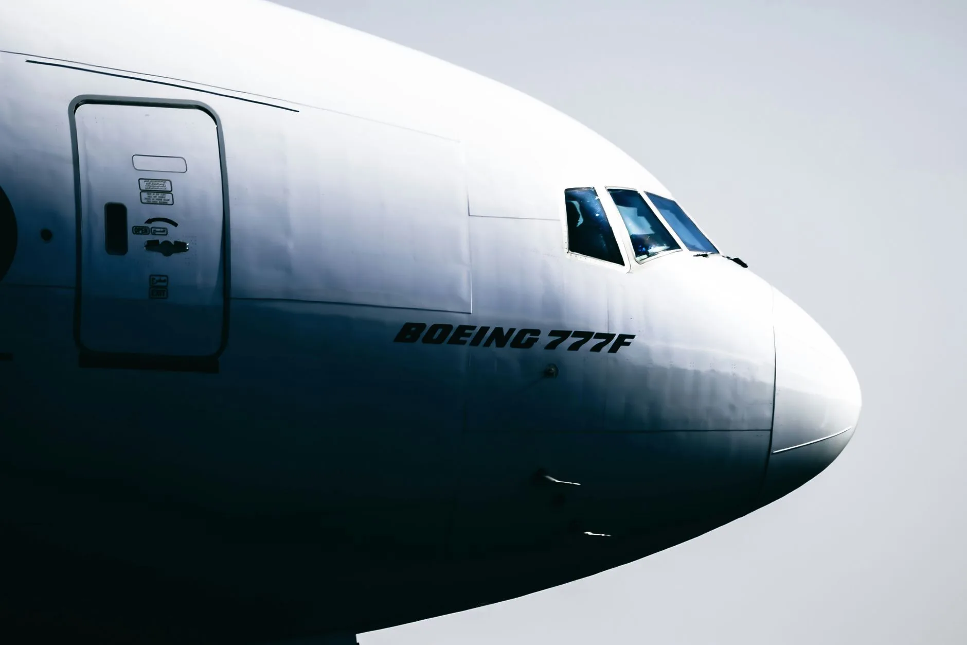 Nahaufnahme des Bugs einer Boeing 777F mit Cockpitfenstern vor hellem Himmel