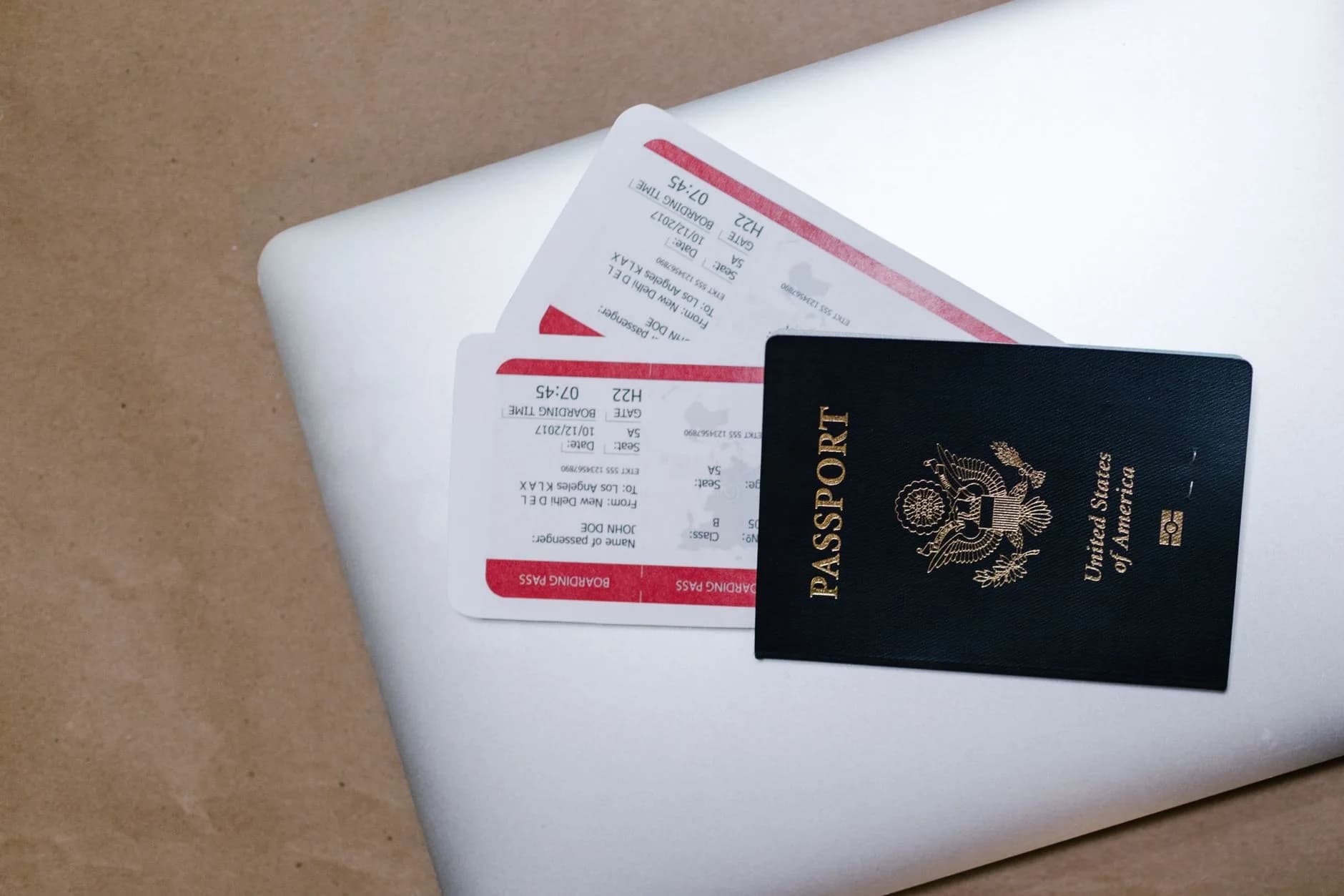 Reisepass der USA liegt auf zwei Bordkarten auf einem geschlossenen Laptop