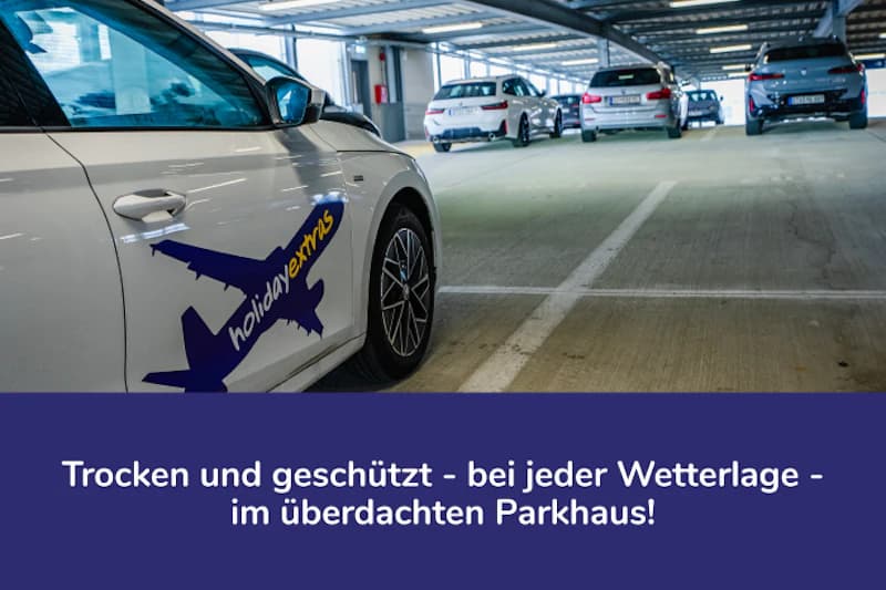 Überdachtes Parkhaus mit mehreren geparkten Autos, im Vordergrund ein weißes Auto mit holidayextras-Aufkleber.