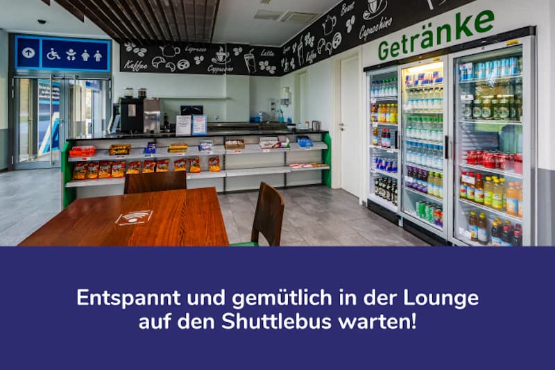 Lounge mit Holztisch, Stühlen, Snackregal und gekühlten Getränkekühlschränken mit Aufschrift Getränke.