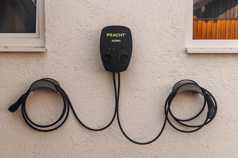Wandladestation PRACHT Alpha mit zwei aufgewickelten Ladekabeln zwischen zwei Fenstern.